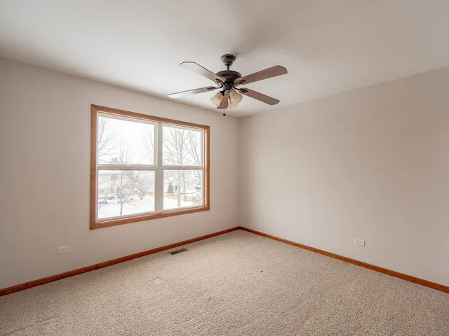an empty room with a window and a ceiling fan