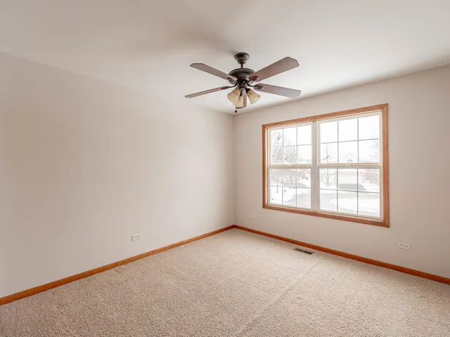 an empty room with a window and a fan