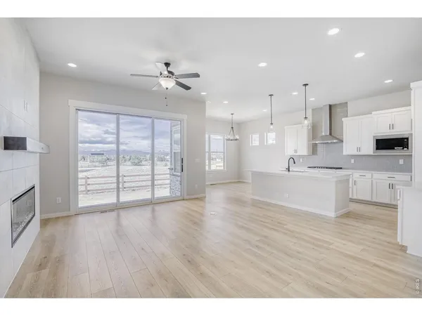 a view of an empty room and kitchen with wooden floor