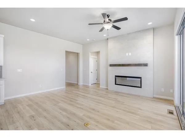 a view of an empty room with wooden floor and a ceiling fan