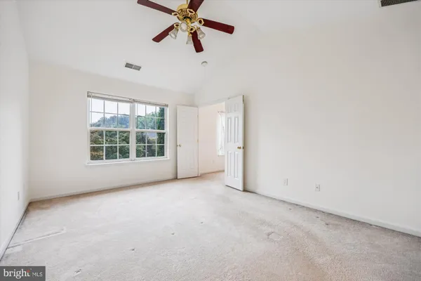an empty room with windows and fan