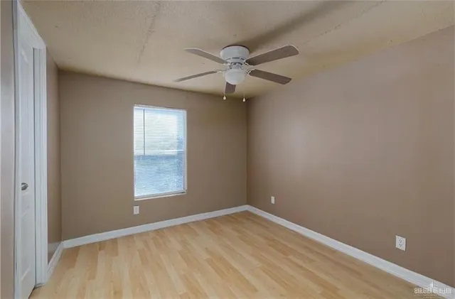 an empty room with a window and a ceiling fan