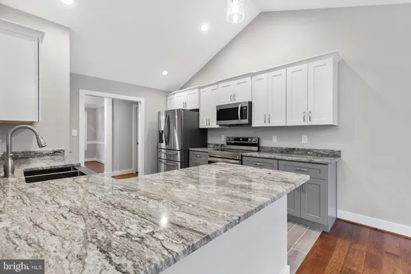 a kitchen with granite countertop a sink appliances and cabinets