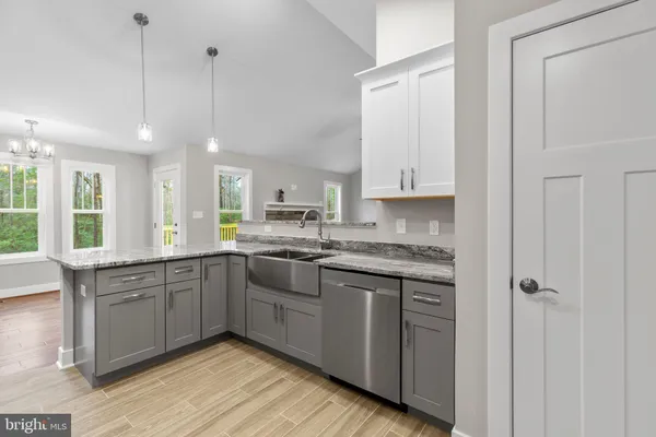 a large kitchen with stainless steel appliances granite countertop a stove a sink and white cabinets with wooden floor