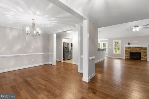 an empty room with wooden floor fireplace and chandelier