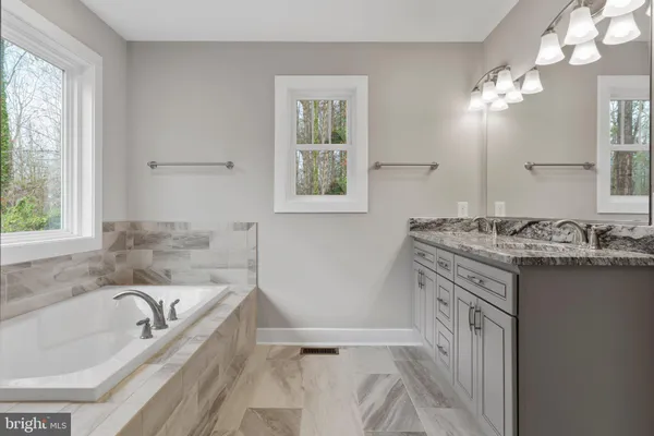 a bathroom with a granite countertop tub sink and mirror