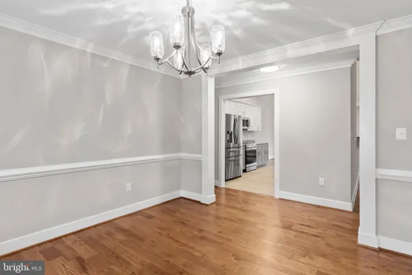 a view of a hallway with wooden floor and a chandelier