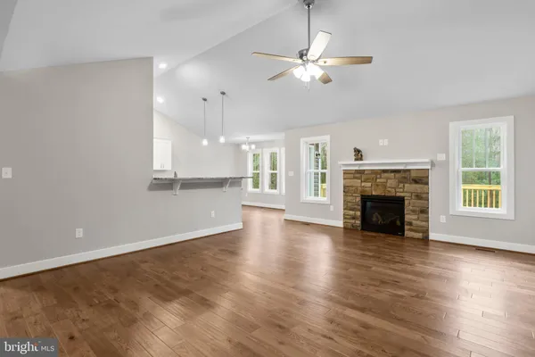 an empty room with wooden floor fireplace and windows
