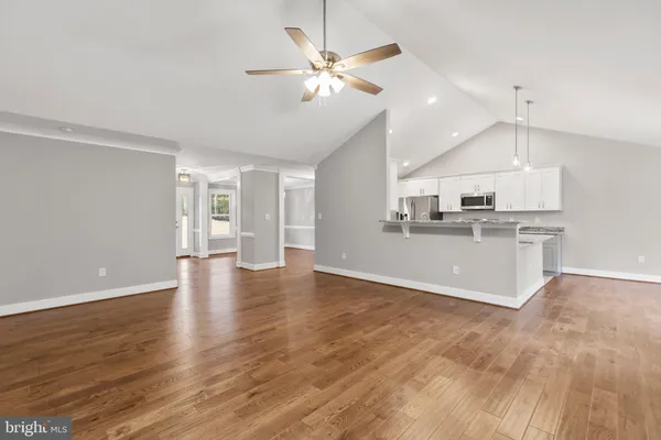 a view of a kitchen with a kitchen island wooden floor and a ceiling fan