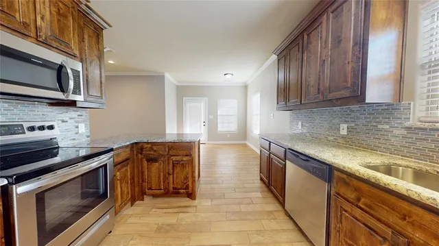 a kitchen with stainless steel appliances granite countertop a stove a sink and a microwave