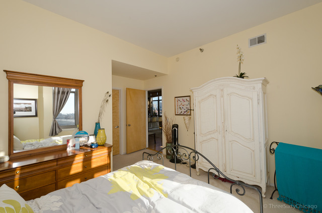 1201 West Adams Street, Unit 905 Chicago, IL 60607 - Photo 11 of 19 a bedroom with a bed and a dresser with mirror