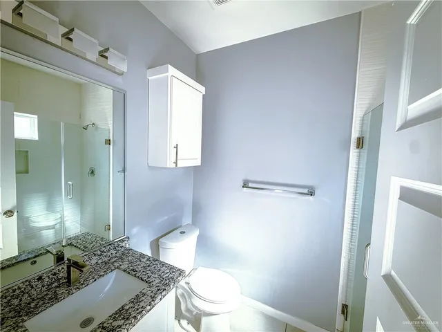 a bathroom with a granite countertop sink a toilet and shower