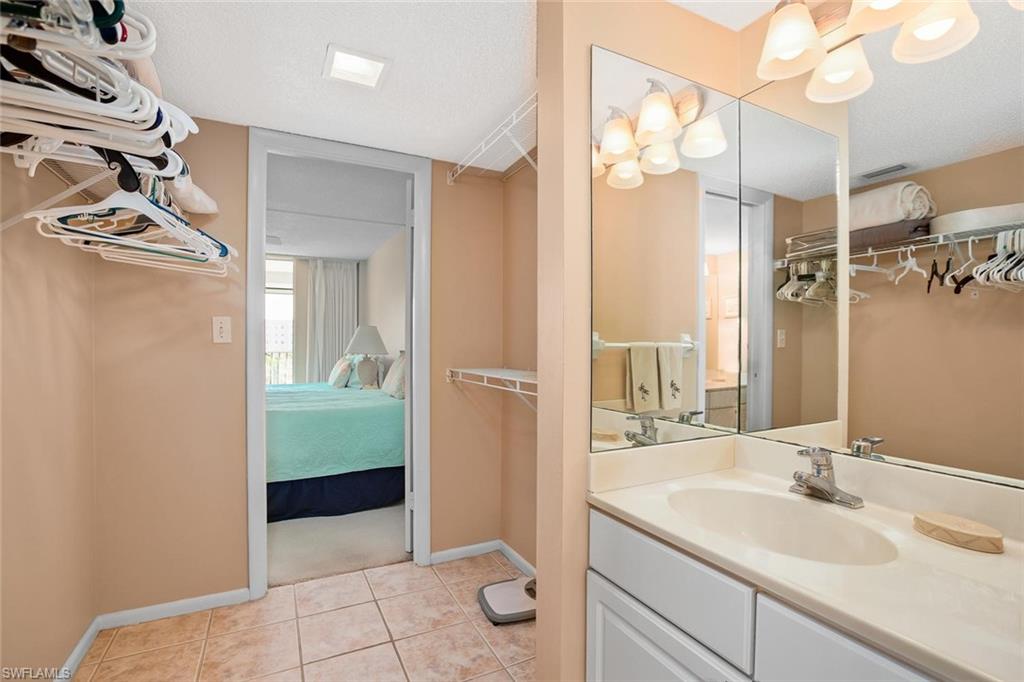 3 Bluebill Avenue, Unit 610 Naples, FL 34108 - Photo 14 of 15 a bathroom with a granite countertop sink a mirror and a shower