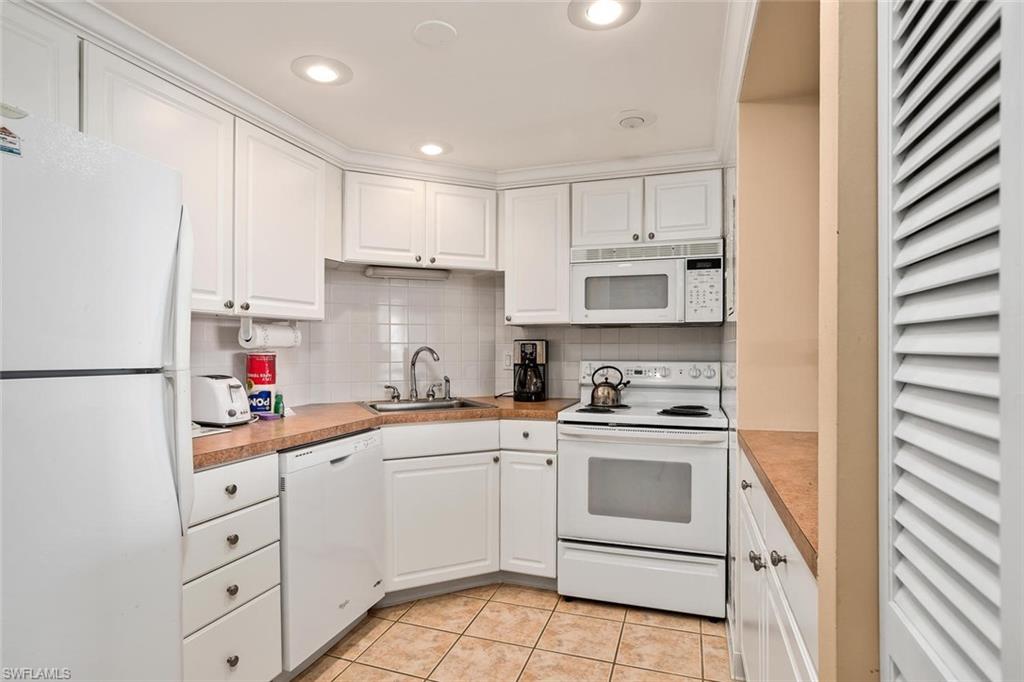 3 Bluebill Avenue, Unit 610 Naples, FL 34108 - Photo 6 of 15 a kitchen with white cabinets sink and white appliances