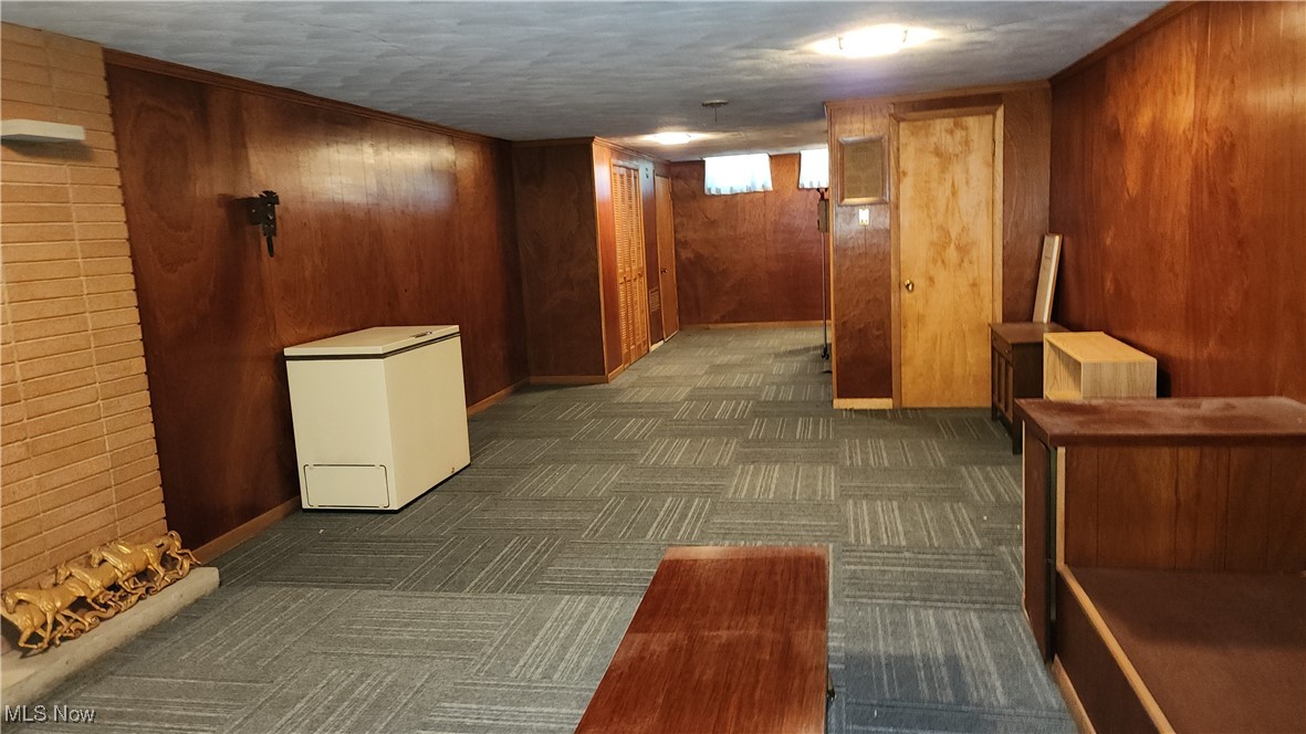 8355 Dalepoint Road Independence, OH 44131 - Photo 19 of 27 Hallway featuring baseboards, dark colored carpet, and wood walls