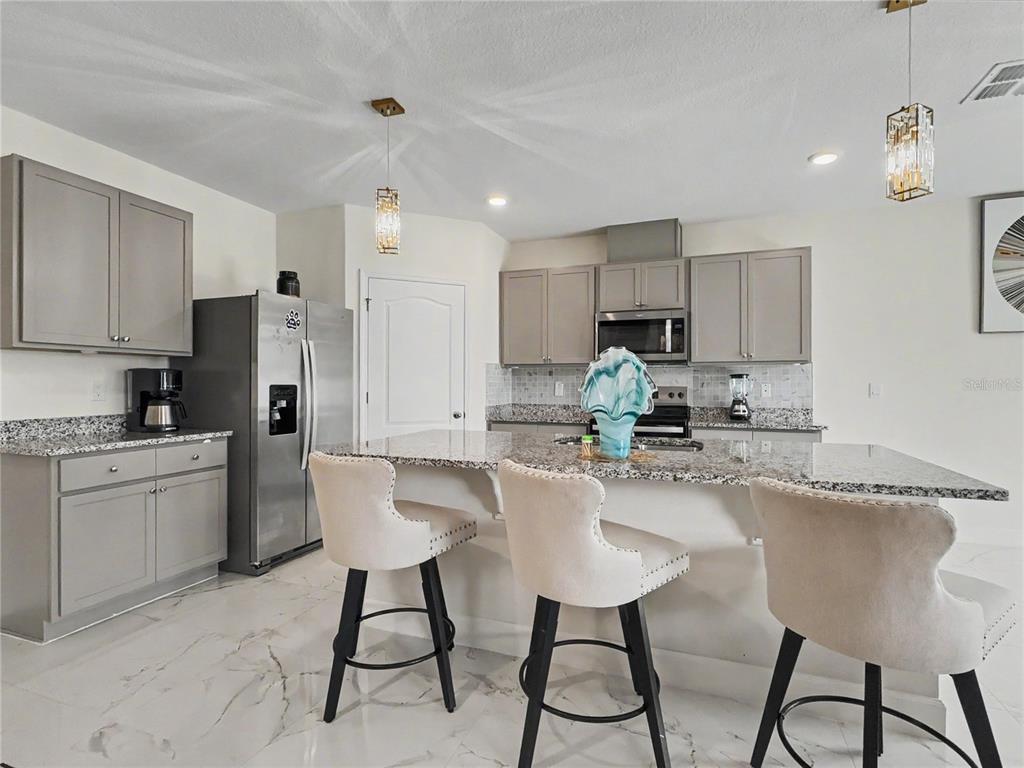 2085 Doe Run Drive Davenport, FL 33837 - Photo 16 of 44 a kitchen with refrigerator and chairs