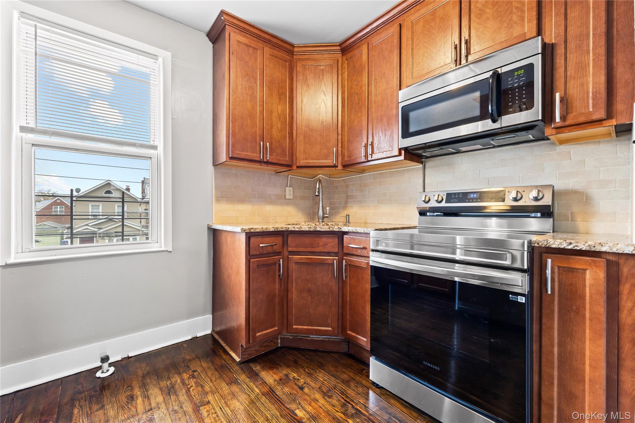 42-25 189th Street Queens, NY 11358 - Photo 13 of 25 a kitchen with stainless steel appliances granite countertop a stove microwave and cabinets