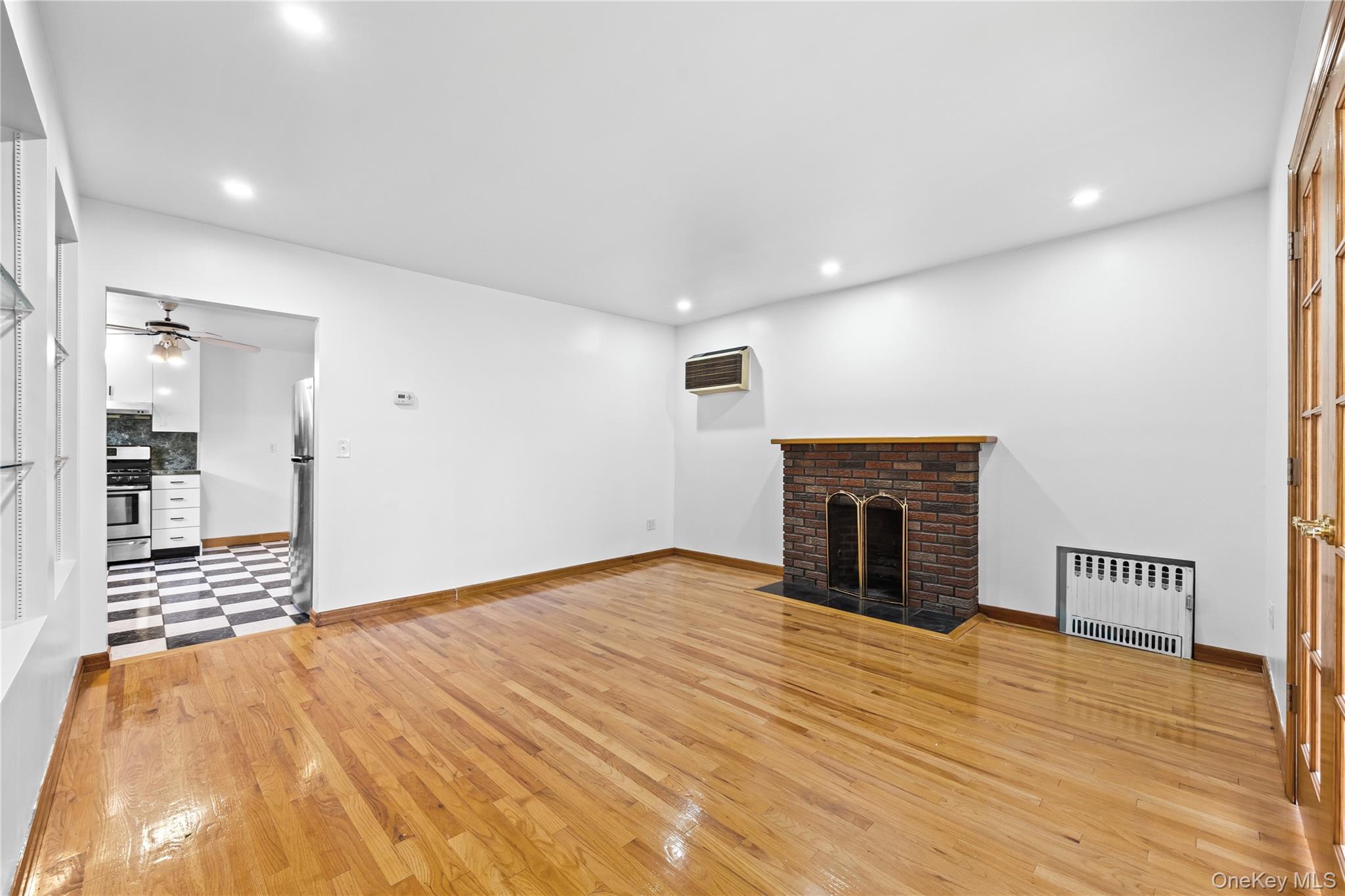 42-25 189th Street Queens, NY 11358 - Photo 4 of 25 a view of empty room with wooden floor and fireplace