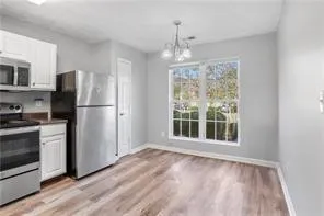 a view of a kitchen with wooden floor electronic appliances and window
