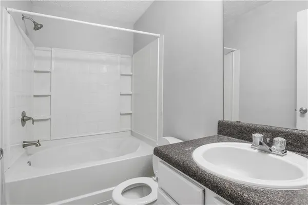 a bathroom with a granite countertop sink a mirror and a bathtub
