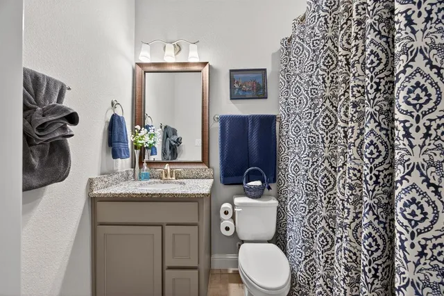 a bathroom with a granite countertop toilet sink and mirror