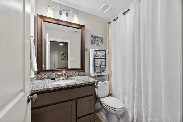 a bathroom with a granite countertop sink toilet and a mirror