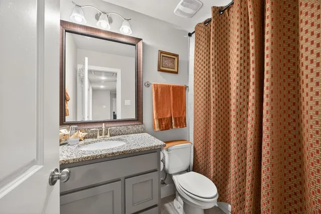 a bathroom with a granite countertop toilet sink and mirror