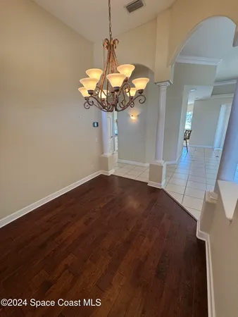 a view of a room with wooden floor chandelier and windows