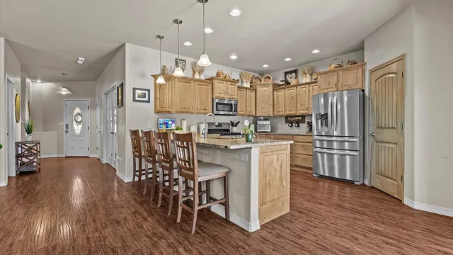 a kitchen with stainless steel appliances kitchen island granite countertop wooden floors and cabinets