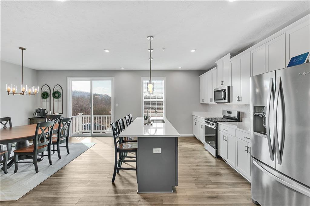 107 Affinity Drive Harmony, PA 16037 - Photo 9 of 49 a kitchen with stainless steel appliances granite countertop a refrigerator a stove a sink a dining table and chairs with wooden floor