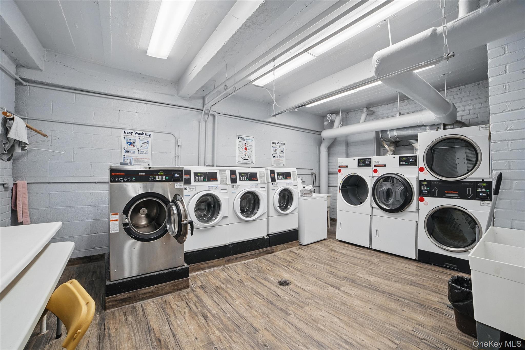 682 Tuckahoe Road, Unit 1A Yonkers, NY 10710 - Photo 18 of 21 Shared laundry featuring wood finished floors, washer and clothes dryer, stacked washer / drying machine, and concrete block wall