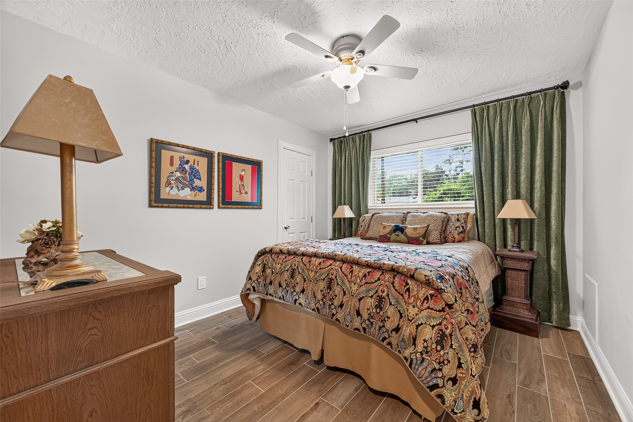 24719 Wilderness Road Spring, TX 77380 - Photo 21 of 42 This cozy bedroom features a ceiling fan, wood-style ceramic tile flooring, and a large window offering natural light.