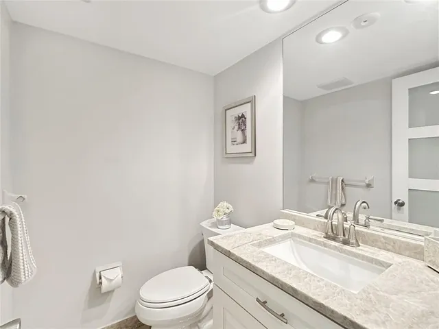 a bathroom with a granite countertop sink a toilet and a mirror