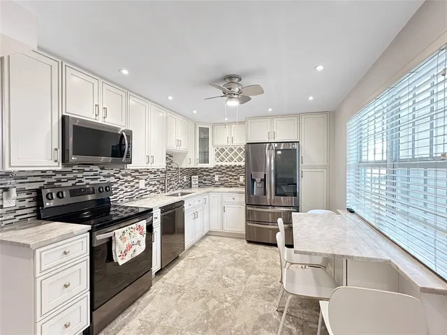 a large kitchen with stainless steel appliances granite countertop a stove top oven a sink dishwasher a dining table and chairs with wooden floor