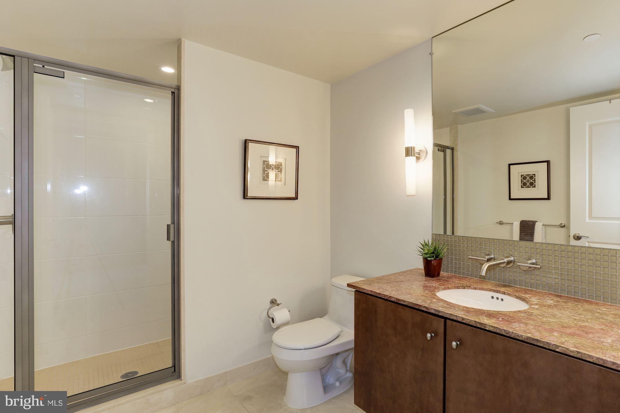 1025 First Street Southeast, Unit 916 Washington, DC 20003 - Photo 21 of 30 a bathroom with a granite countertop toilet sink and mirror