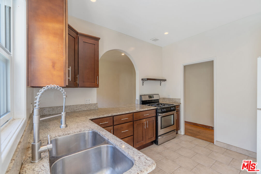 458 North Genesee Avenue Los Angeles, CA 90036 - Photo 16 of 38 a kitchen with stainless steel appliances granite countertop a sink and a stove next to a window