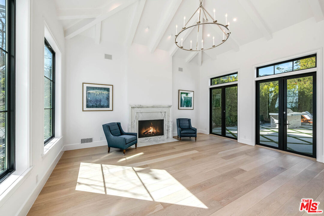 1348 Marinette Road Pacific Palisades, CA 90272 - Photo 6 of 50 a living room with furniture a fireplace and a chandelier