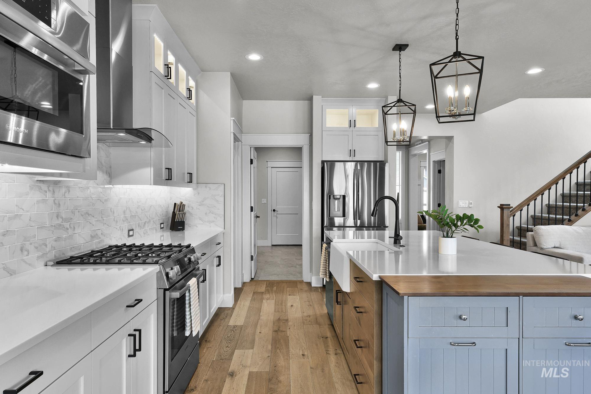 5676 East Zaffre Ridge Street Boise, ID 83716 - Photo 12 of 50 Modern kitchen featuring white shaker cabinetry, stainless steel appliances, a gas range, and wood-finish flooring