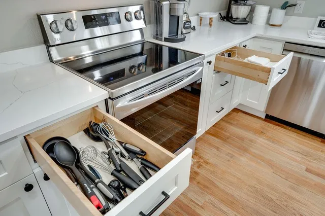 a stove top oven sitting inside of a kitchen with stainless steel appliances wooden floor
