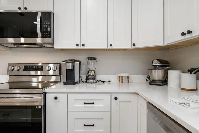 a kitchen with white cabinets and appliances