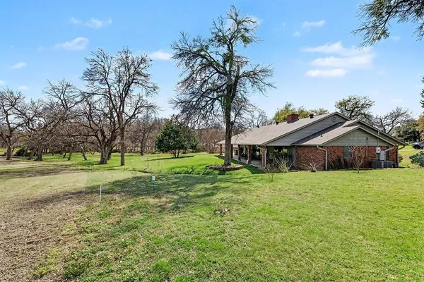 a view of a house with a big yard and large trees