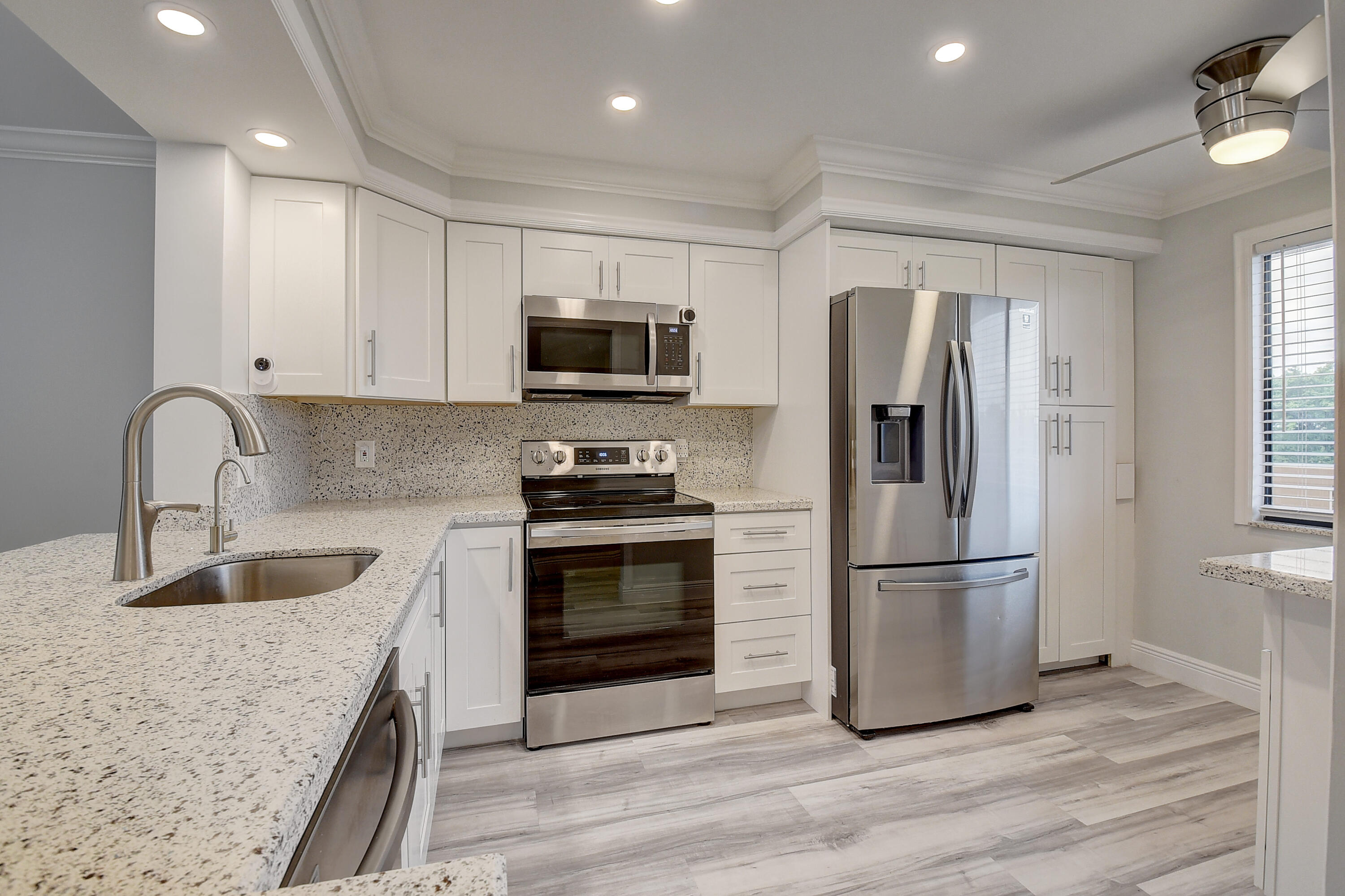7076 Huntington Lane, Unit 507 Delray Beach, FL 33446 - Photo 13 of 48 a kitchen with stainless steel appliances granite countertop a refrigerator sink and microwave