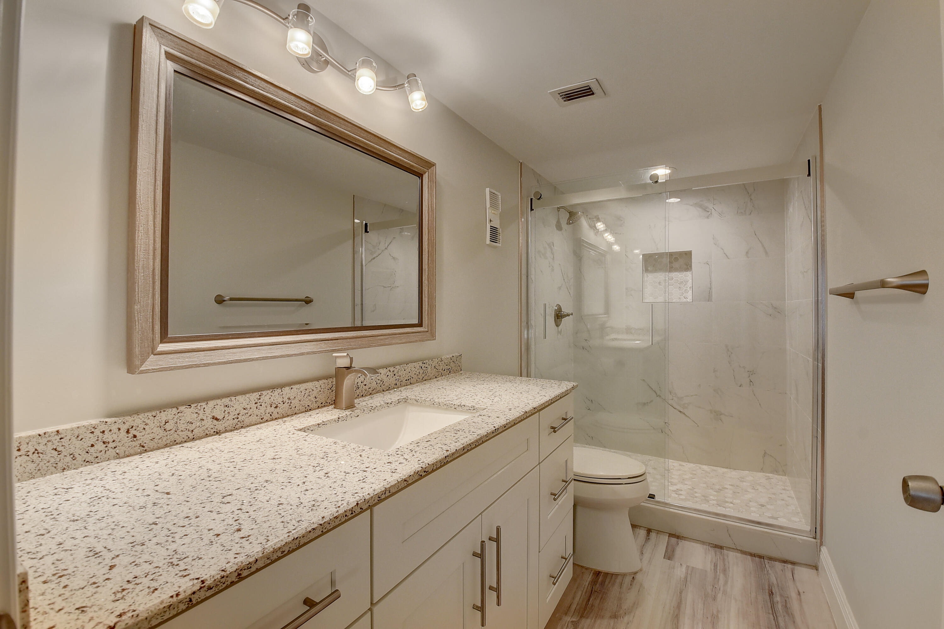 7076 Huntington Lane, Unit 507 Delray Beach, FL 33446 - Photo 19 of 48 a bathroom with a granite countertop sink toilet a large mirror a shower and vanity
