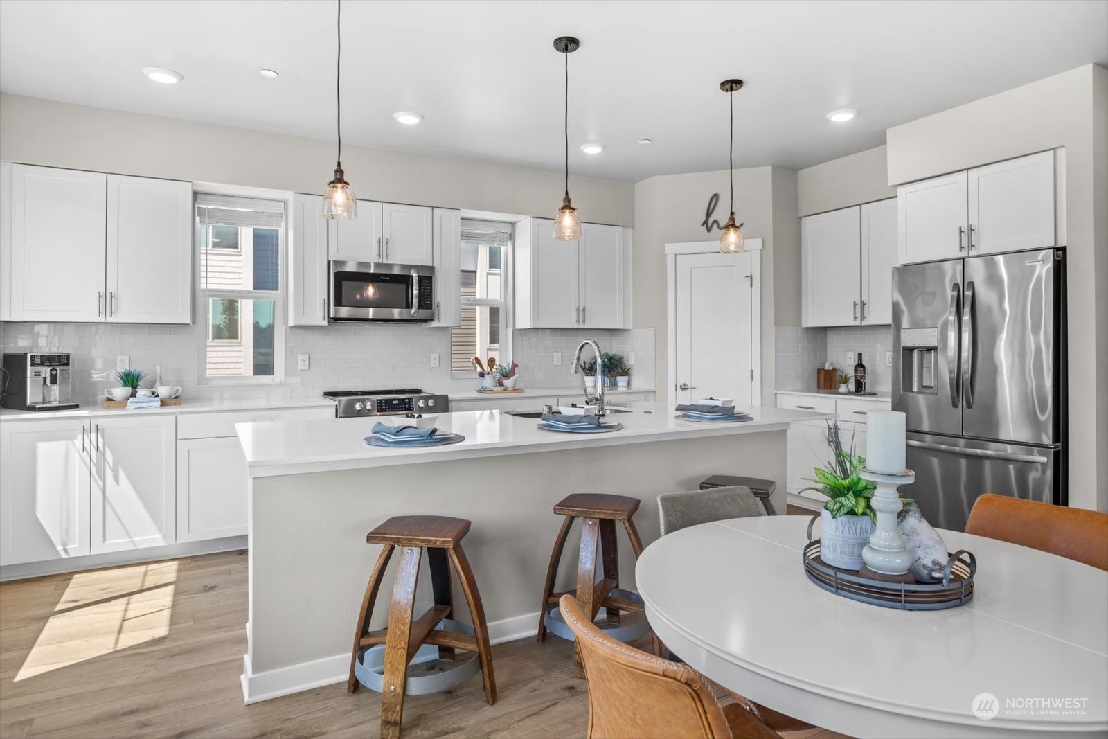 22929 80th Place West, Unit C Edmonds, WA 98026 - Photo 9 of 36 a kitchen with stainless steel appliances granite countertop a refrigerator a stove a sink a dining table and chairs with wooden floor