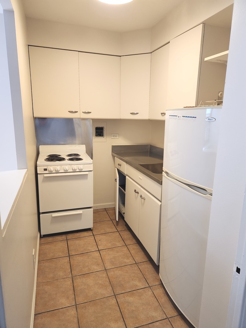 6118 North Sheridan Road, Unit 1206 Chicago, IL 60660 - Photo 5 of 9 a kitchen with a stove a refrigerator and a white cabinets