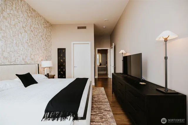 a bedroom with a bed and a flat tv screen on a dresser