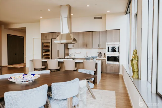 a kitchen with stainless steel appliances kitchen island granite countertop a table chairs and a refrigerator