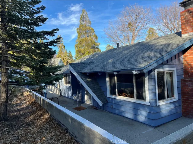 a view of house with a large tree and wooden fence