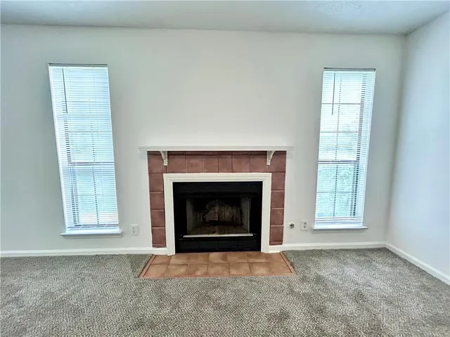 an empty room with windows and fireplace