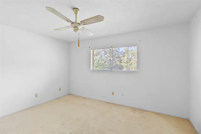 an empty room with a window and a fan